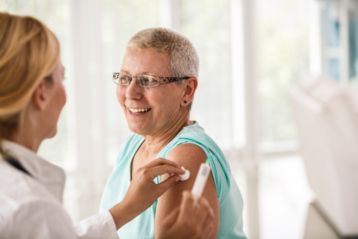 An older woman with glasses meets with her doctor to discuss flu prevention tips